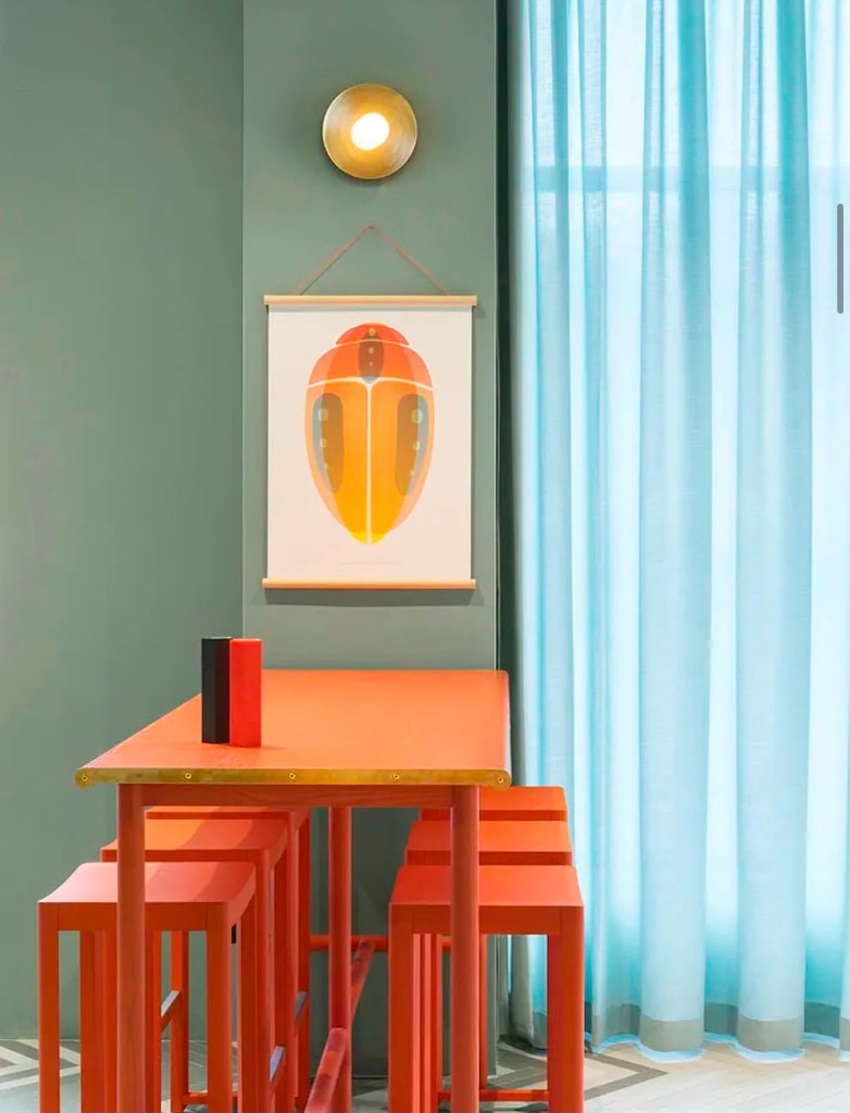 Högt bord med orange pallar och skalbagge-poster på Finefood.